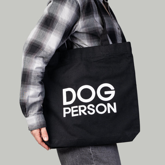 Schwarzer Jutebeutel mit weißem „Dog Person“-Print von Karma Hund, frontal fotografiert.