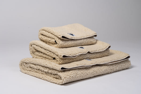 Kompakt gefaltete Kuscheldecke, ideal für unterwegs, mit sichtbarer zweifarbiger Materialkombination.